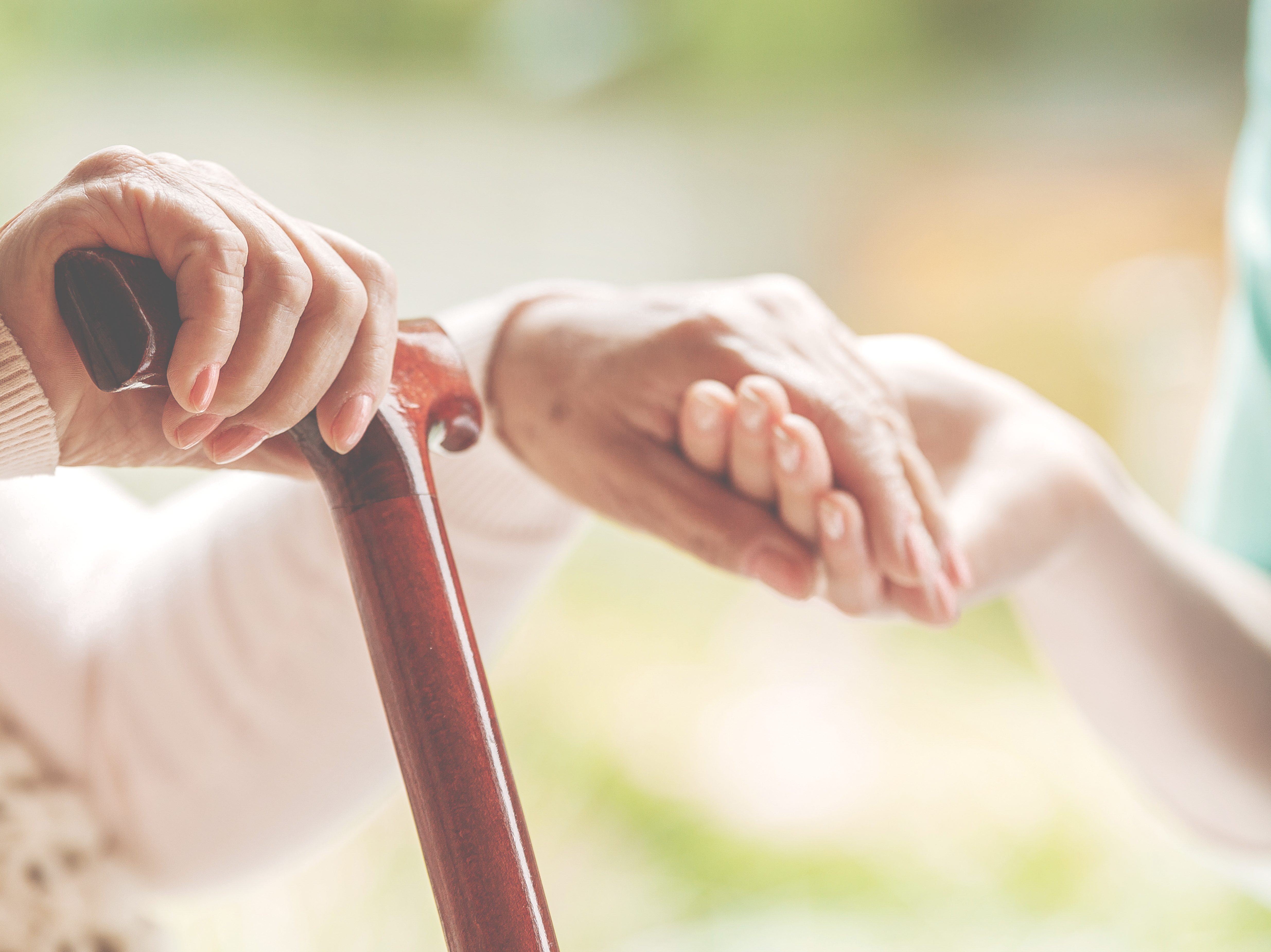 Closeup of senior lady holding walking stick in one hand and hol